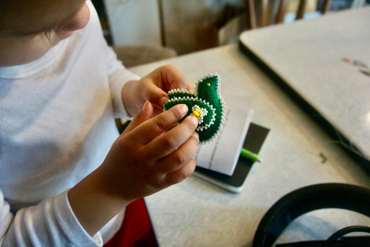 Little girl holding green beaded bird 